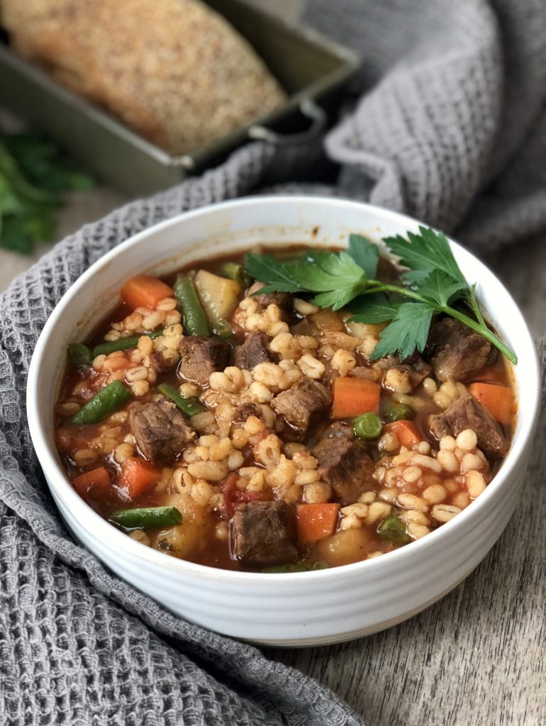 Beef barley soup in a bowl wrapped in a large cloth napkin
