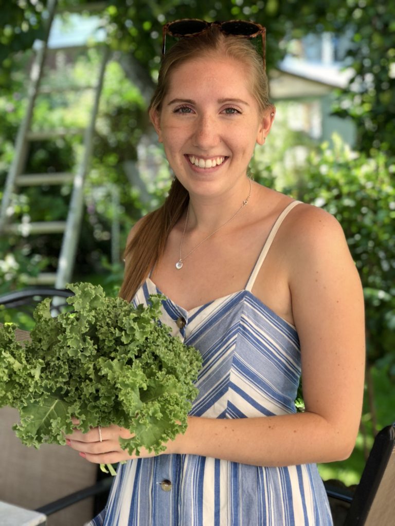 Woman holding bunch of kale in garden