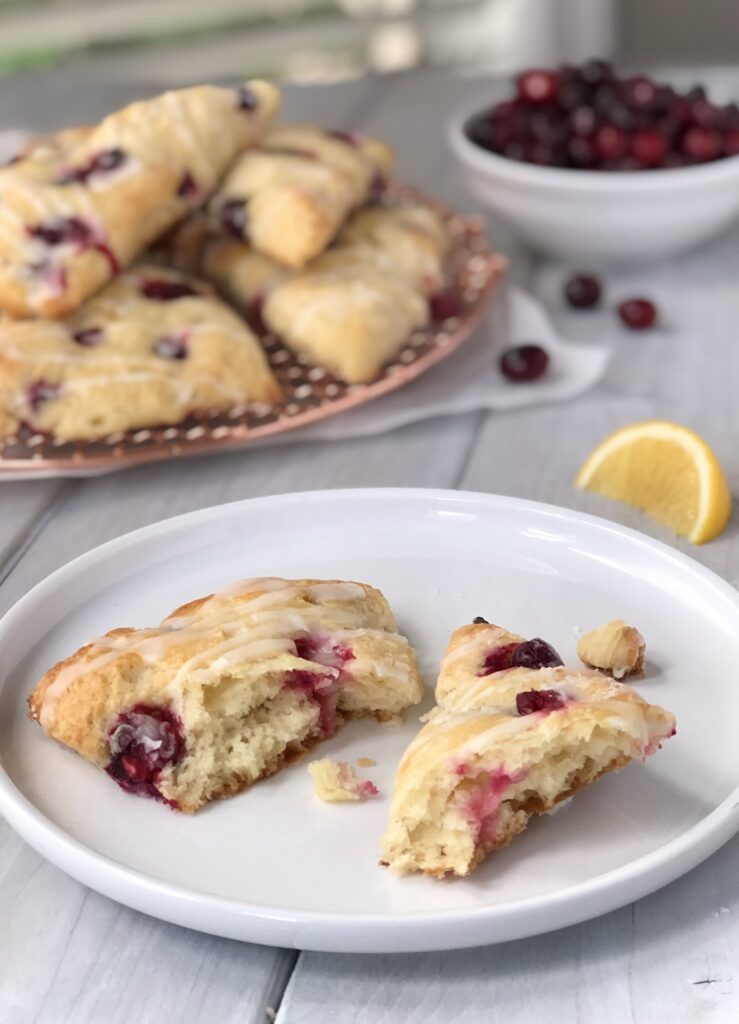 Scone cut open on a plate with more cranberry scones in background.