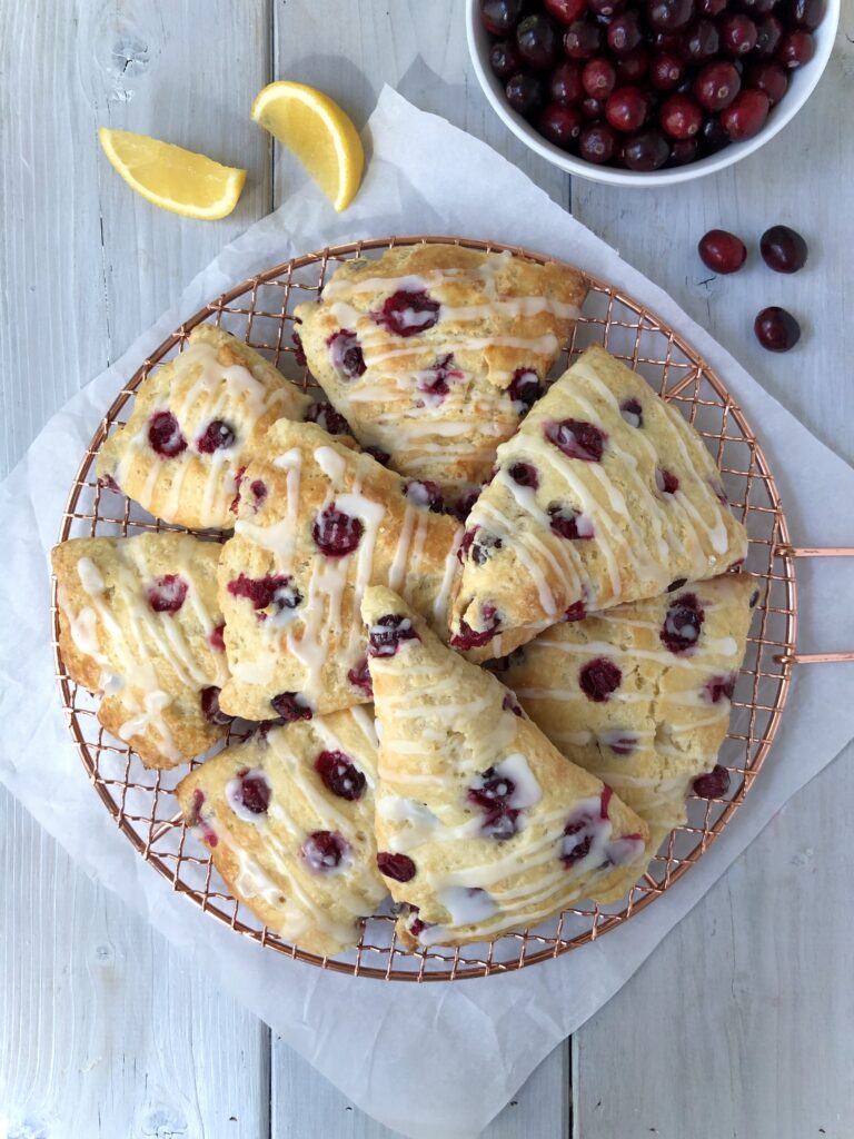  Lemon cranberry scones on a gold rack with bowl of cranberries.