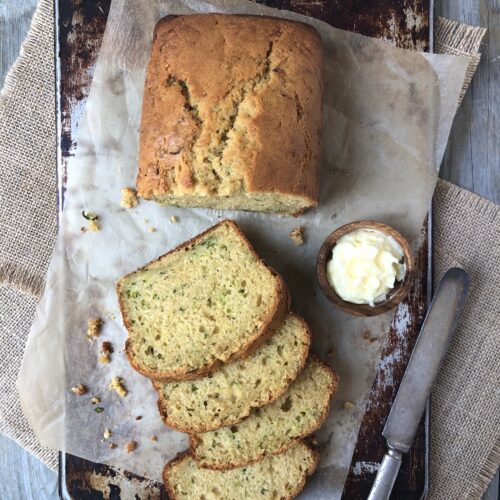 Lemon Zucchini Loaf, half sliced on parchment paper