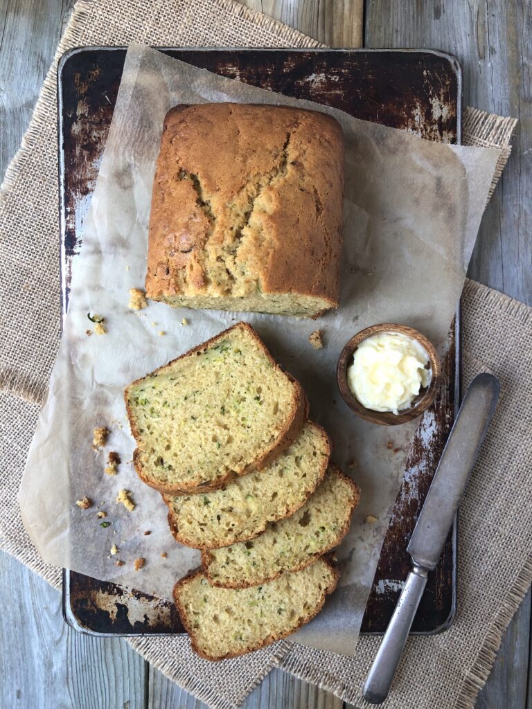 Lemon Zucchini Loaf, half sliced on parchment paper