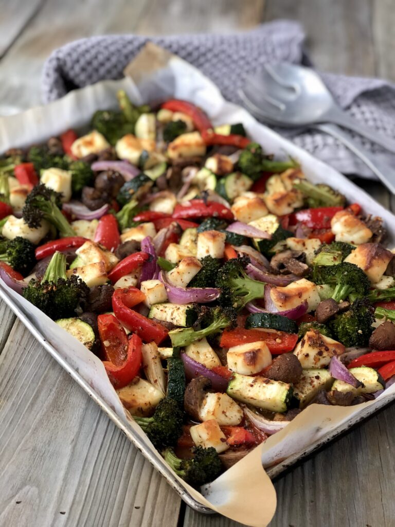 Halloumi and vegetables baked on a sheet pan.