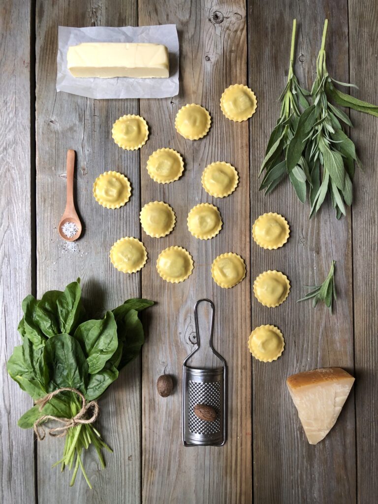 Ravioli, spinach, parmesan and butter arranged on wooden board