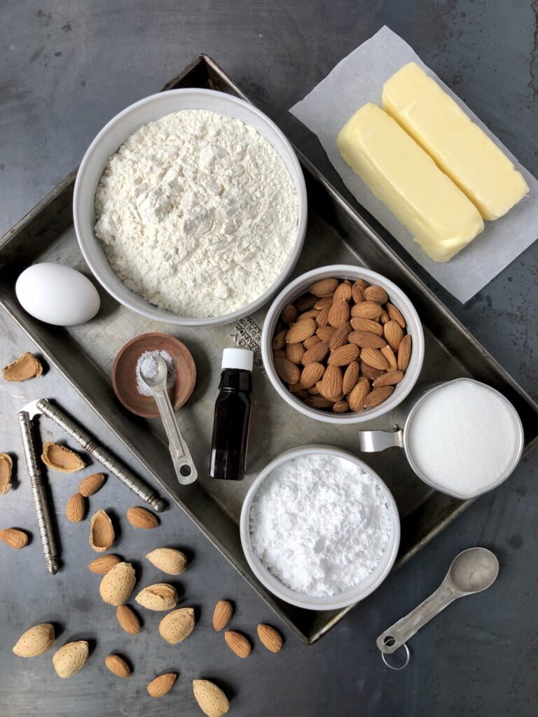 Flour, almonds, sugar, butter, egg, vanilla and other ingredients on a tray