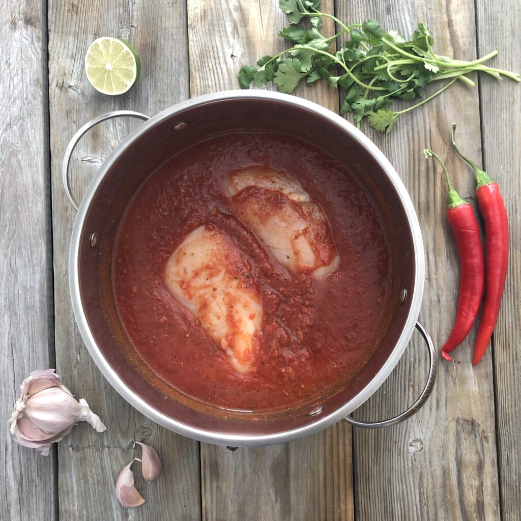 Chicken breasts in pot with crushed tomatoes