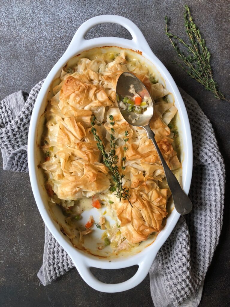 Spooning out baked phyllo topped chicken pot pie.