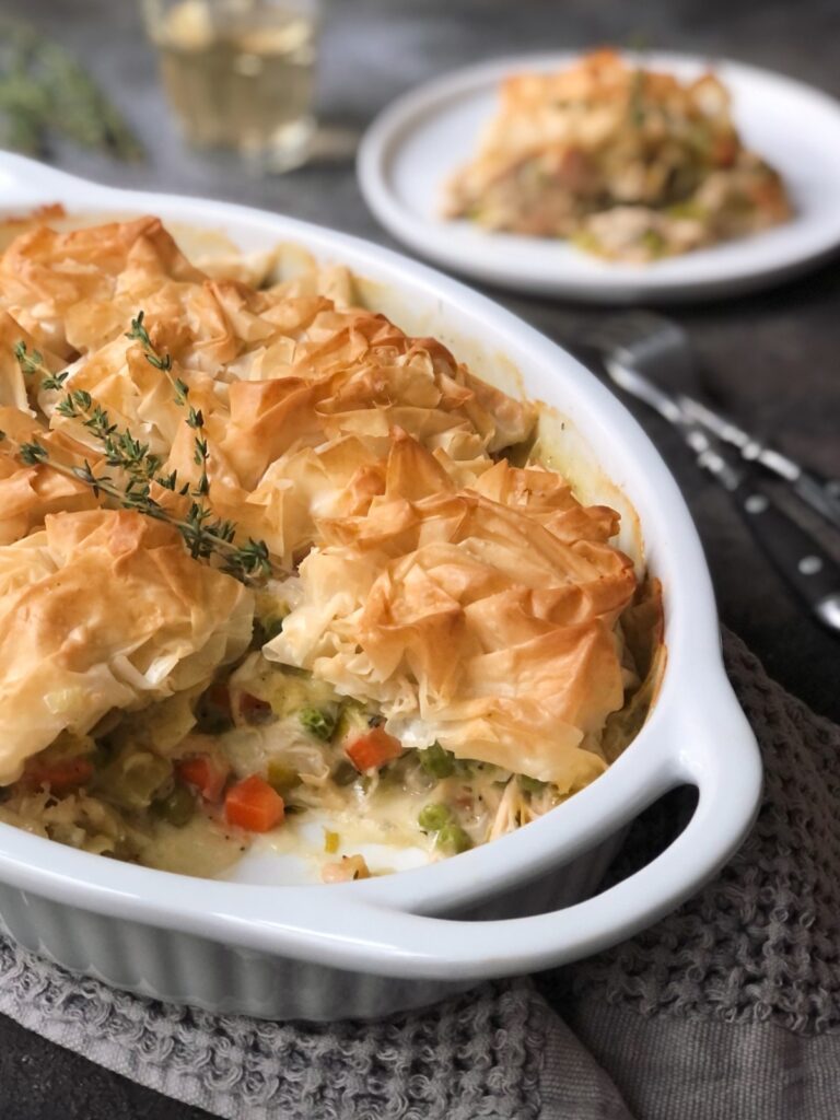Pot pie in casserole dish and a portion on a plate.
