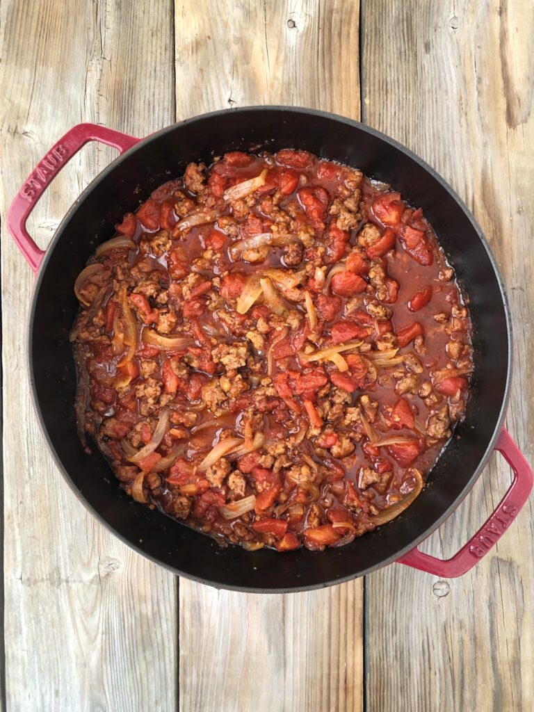 Tomatoes added to sausage and onions in skillet and cooked to thicken