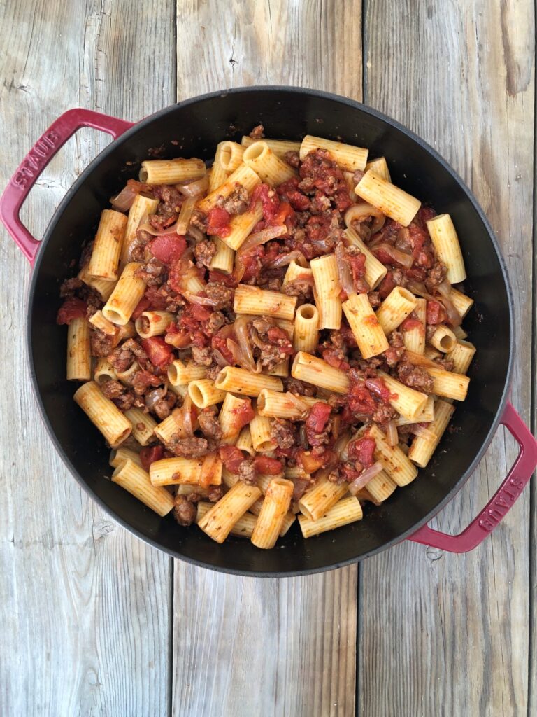 Rigatoni pasta added and tossed with tomato sausage sauce in skillet