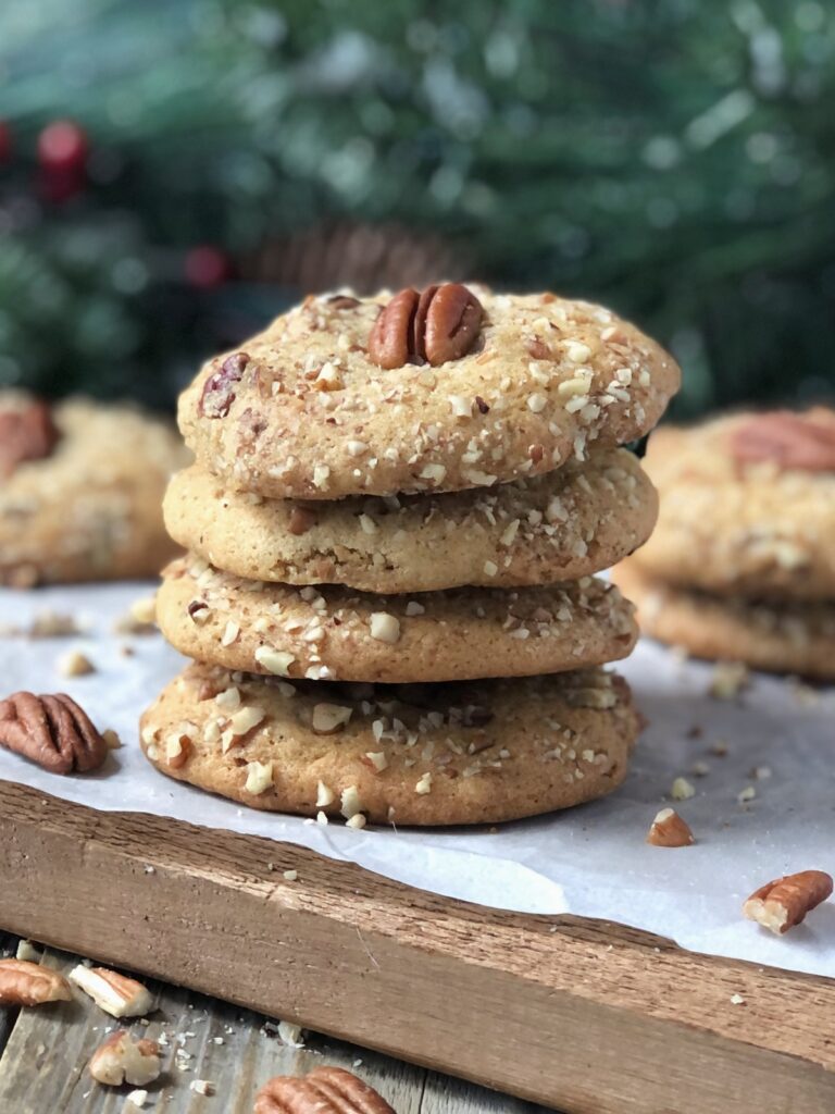 Thick, nutty brown butter pecan cookies stacked on wood board