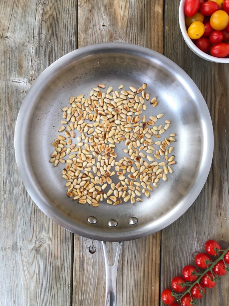 Pine nuts being toasted in a skillet.