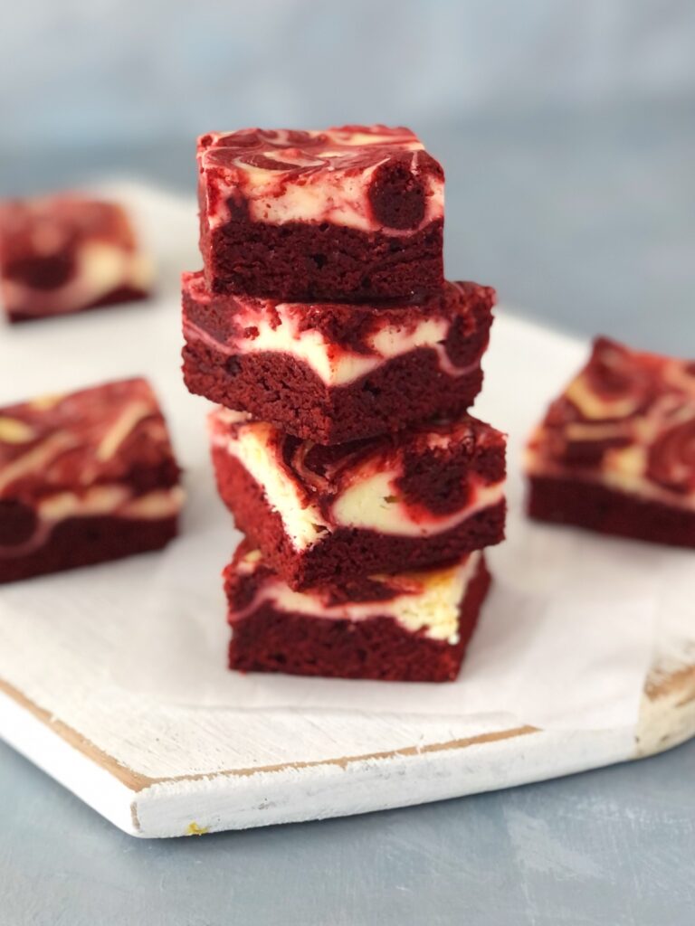 A stack of four moist red velvet cheesecake brownies.