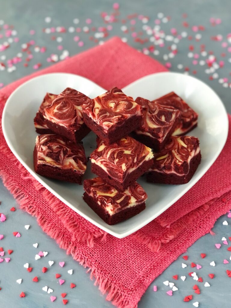 Brownie cheesecake bars piled on a heart-shaped serving plate.