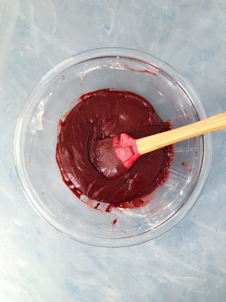 Brownie batter mixed in a clear bowl with a spatula.