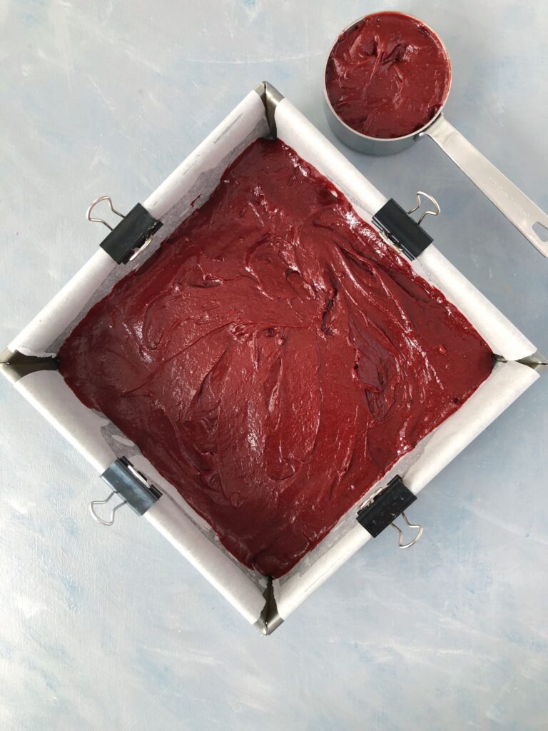 Red velvet brownie batter spread in baking pan.
