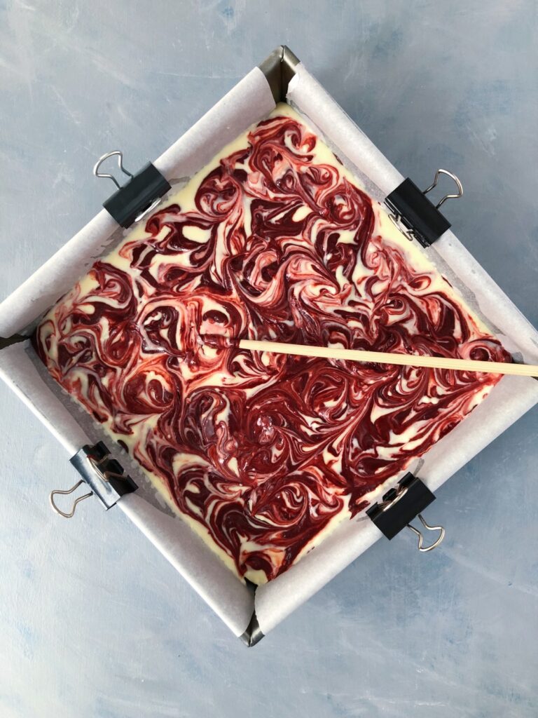 Swirling cheesecake batter in the pan with a chopstick.