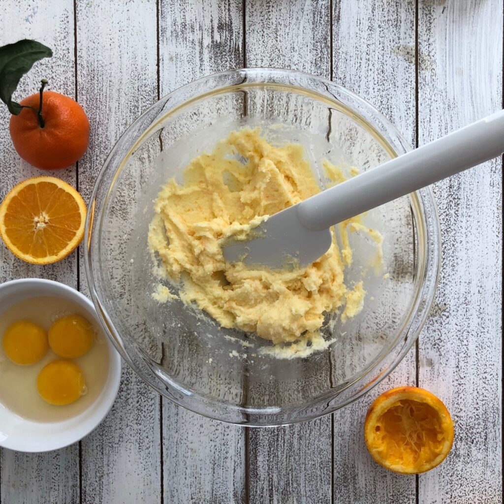 Butter and sugar being mixed in a clear bowl.