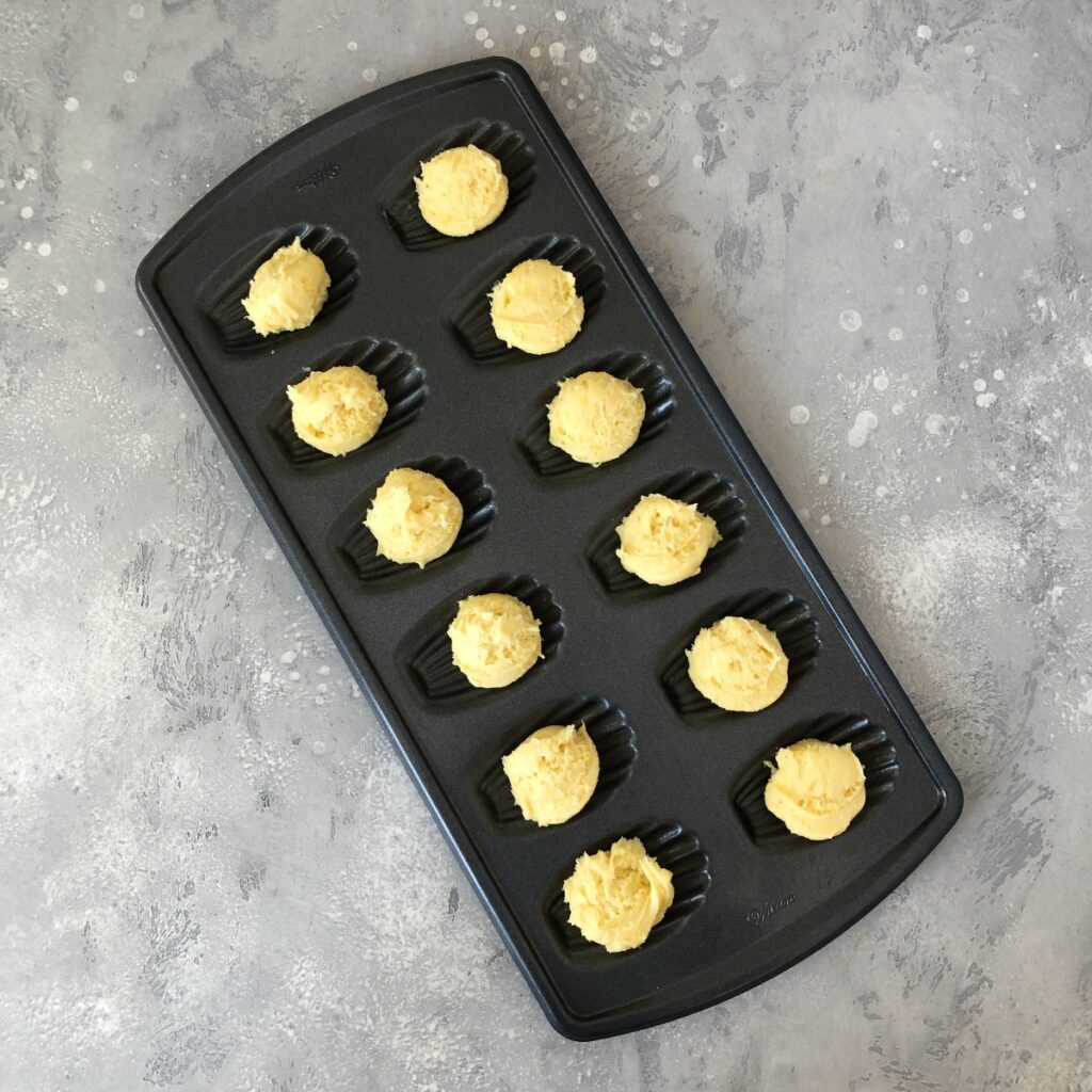 Batter spooned into madeleine pan cavities.