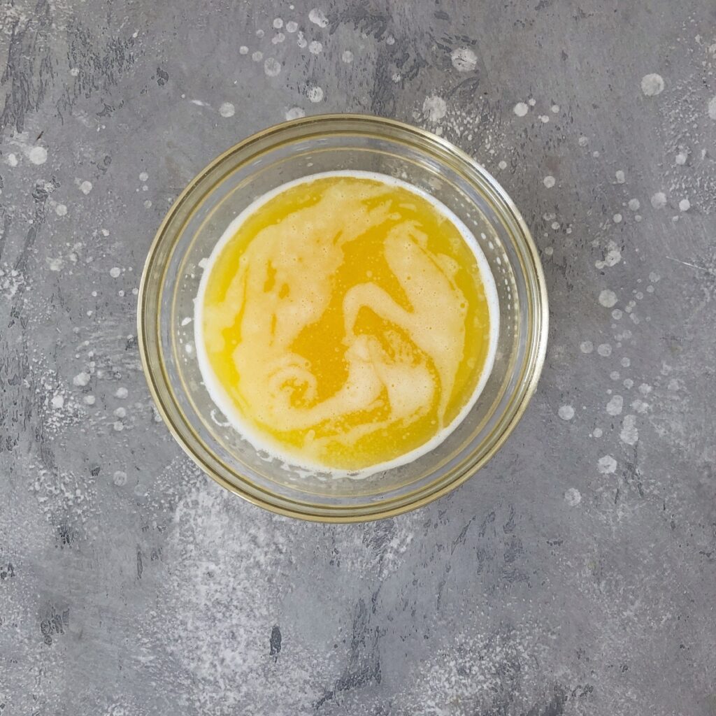 Melted butter cooling in a glass bowl.