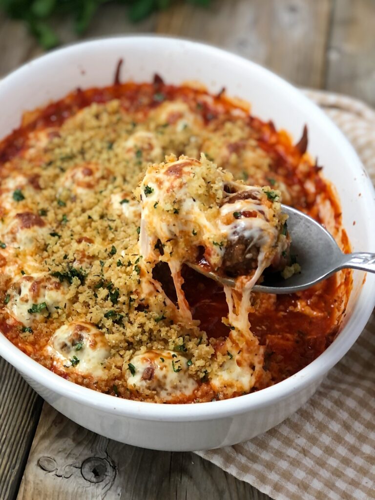 Casserole dish hot out of oven with melty cheese and meatballs.