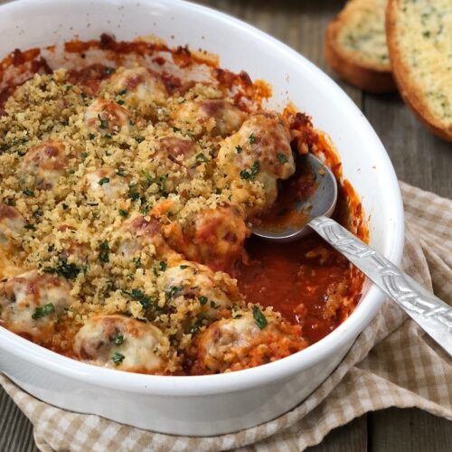Baked meatball casserole being served with a spoon.