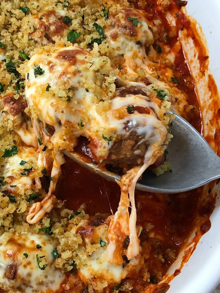 Baked meatballs on a spoon with a cheesy pull.