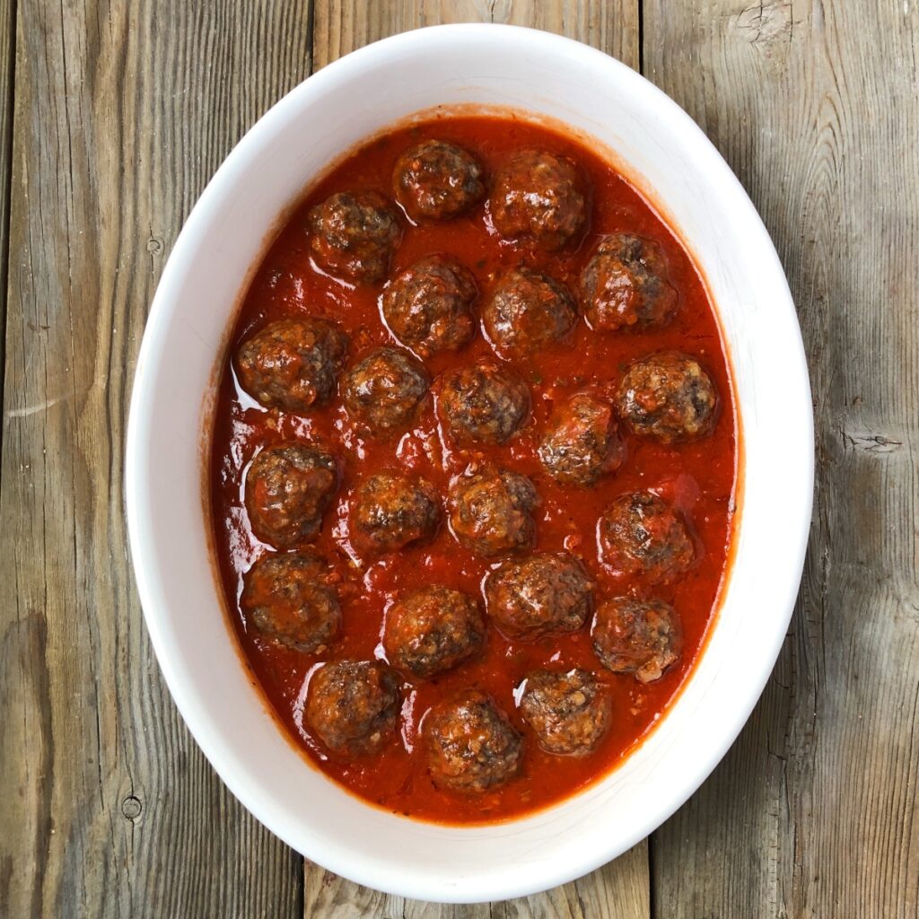 Baked meatballs nestled in tomato sauce.
