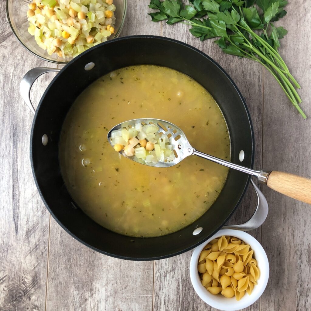 Slotted spoon removing portion of vegetables.