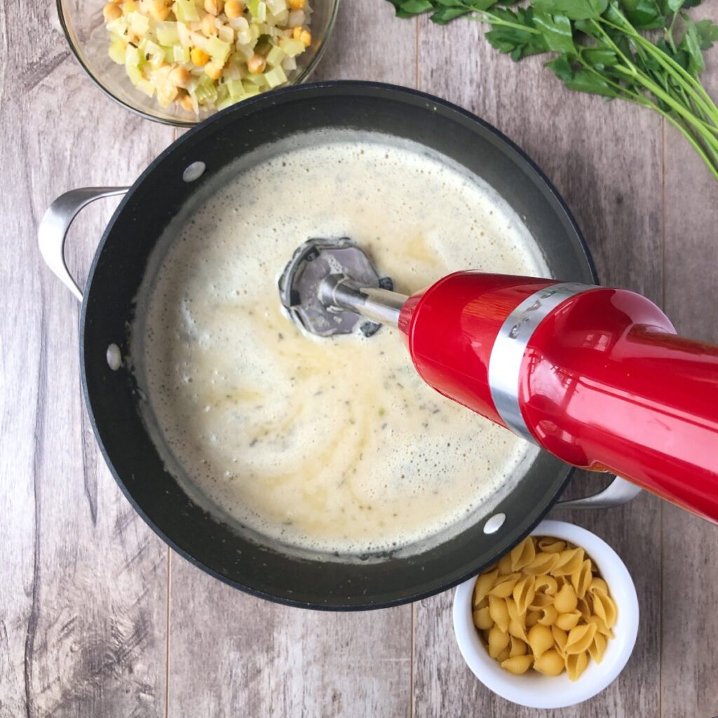 Immersion blender in pot pureeing the soup.