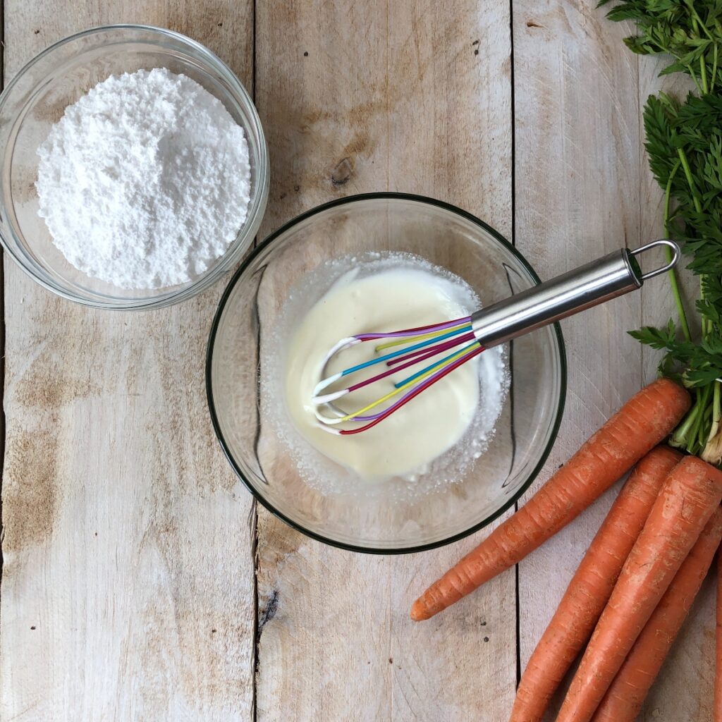Cream cheese and cream whisked together in a bowl.