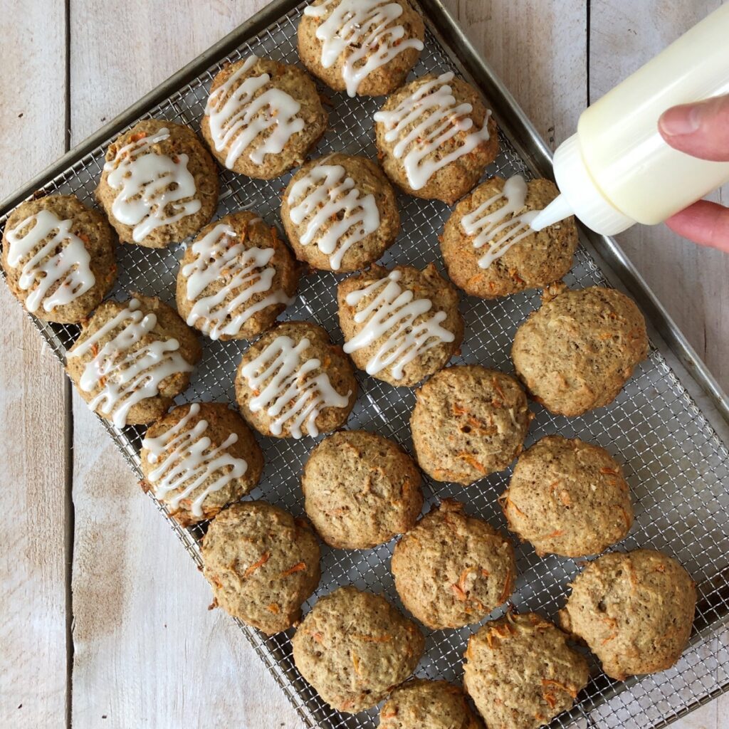 Frosting in a bottle being drizzled over baked cookies.