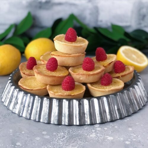 Square image of lemon tarts arranged on a metal tin.