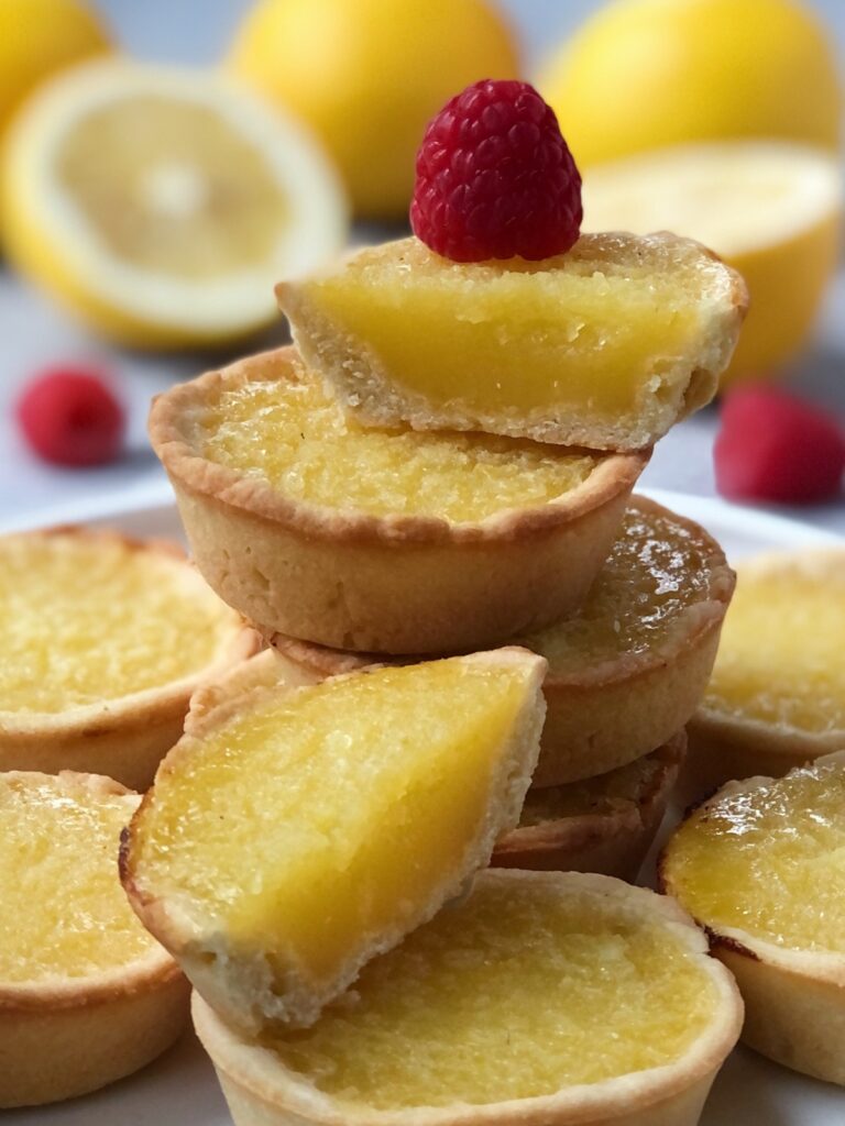 Close-up of a sliced tart stacked with more lemon tarts under it.