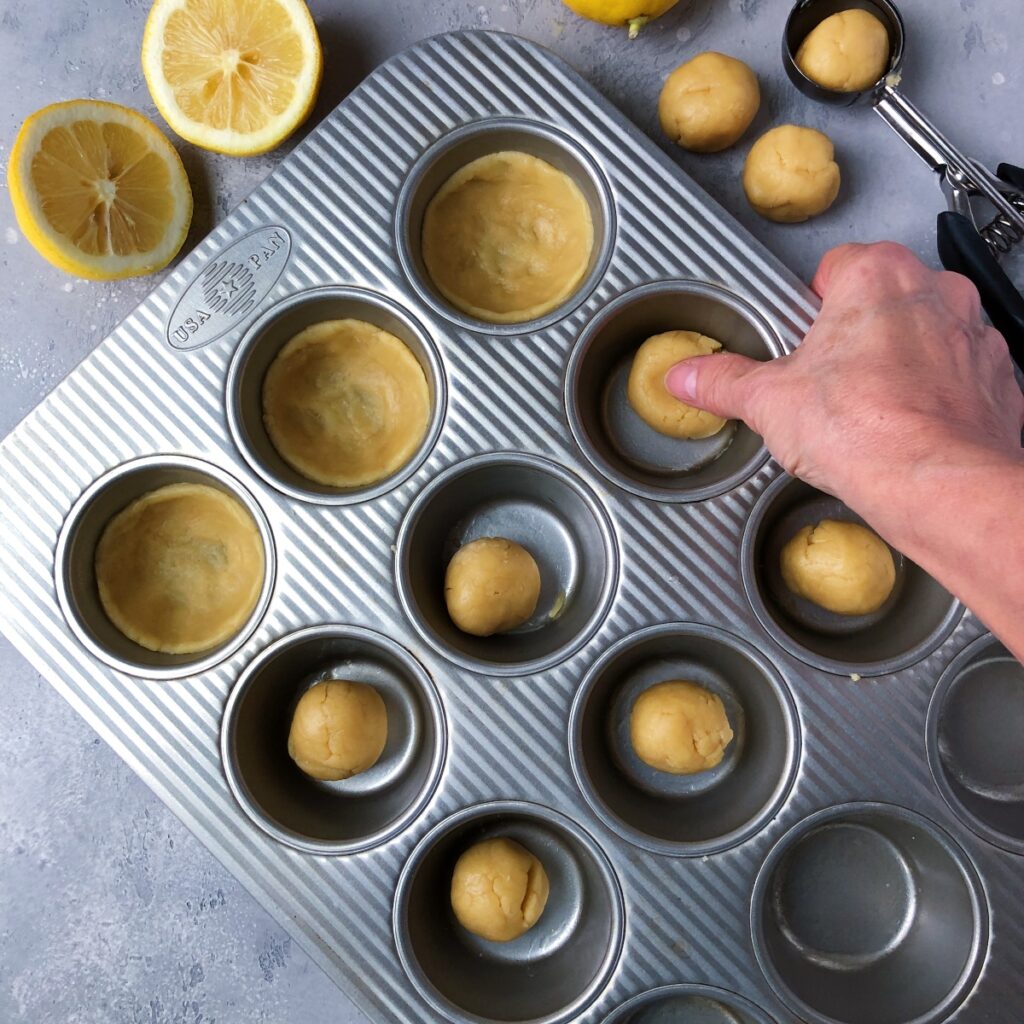 Dough being formed into balls then pressed into muffin cups.