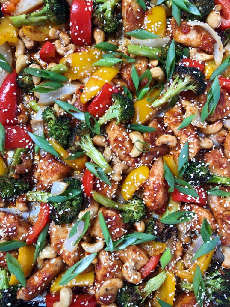 Top down closeup view of cooked sheet pan cashew chicken and vegetables.