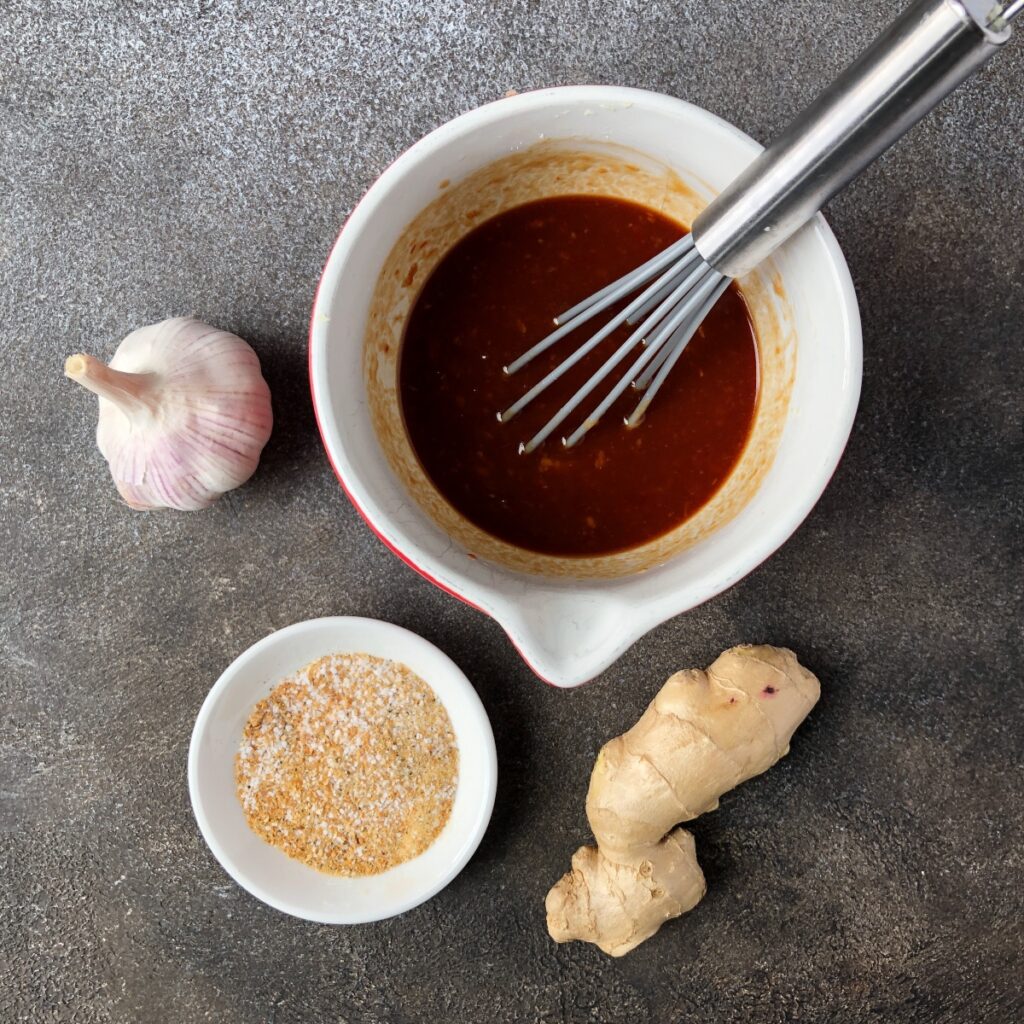 Bowl with sauce ingredients being mixed with a whisk.